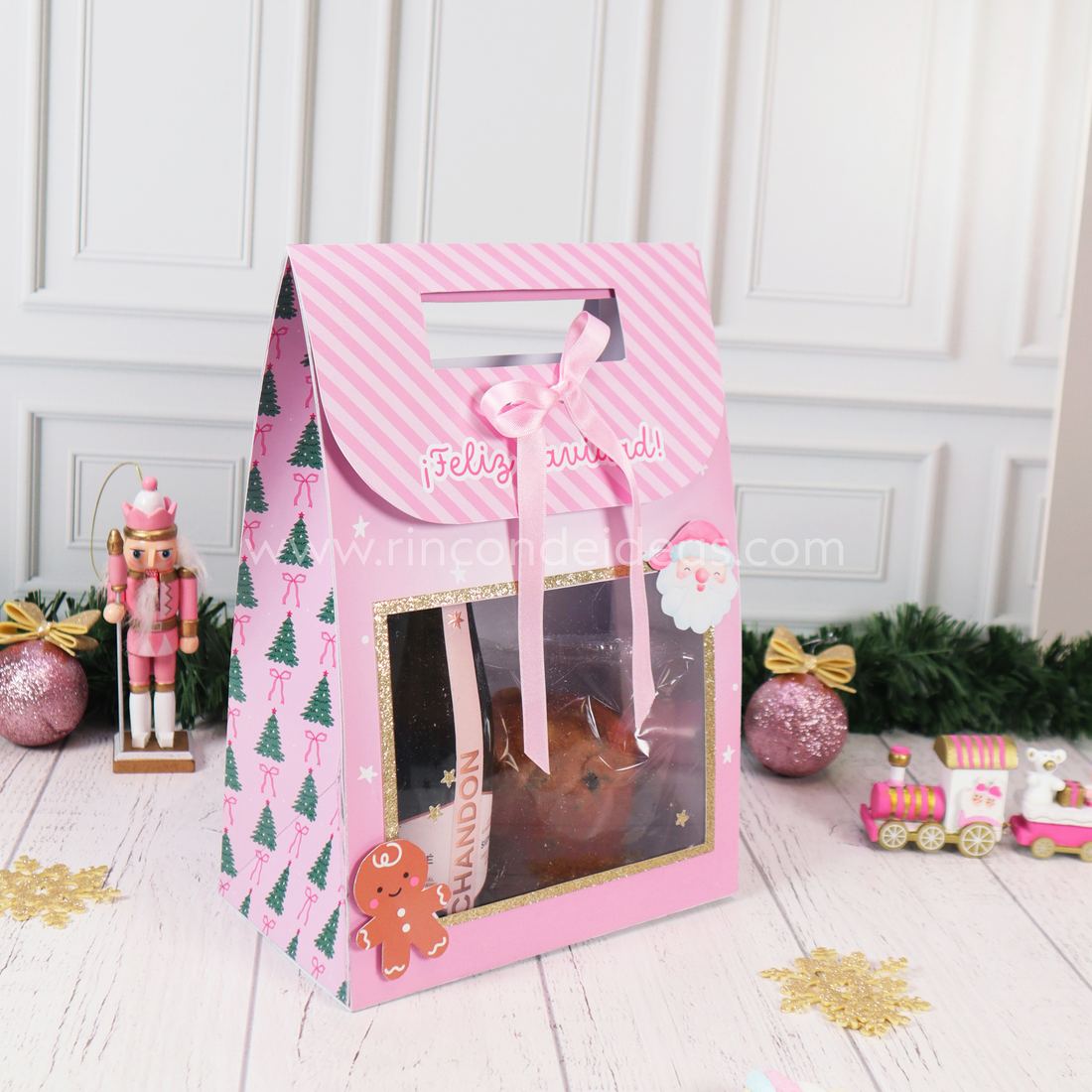 Bolsa con visor rosa en ángulo, con lateral de arbolitos, tapa que dice ¡Feliz Navidad! y moño rosa · Masterclass de Navidad 2026