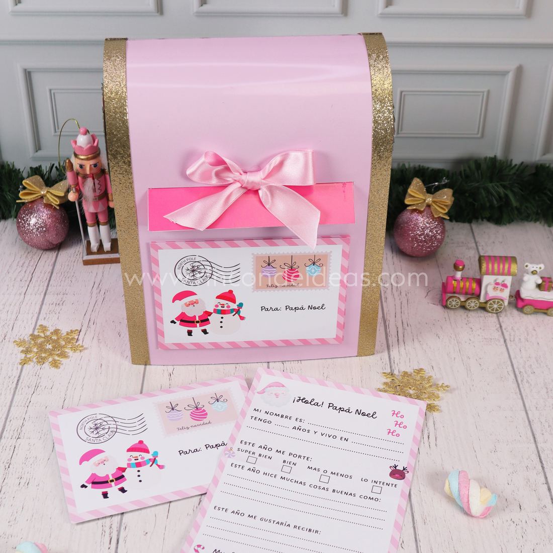 Buzón de Papá Noel rosa y dorado de cerca, con ranura fucsia, moño y sobre con sello del Polo Norte · Masterclass de Navidad 2026