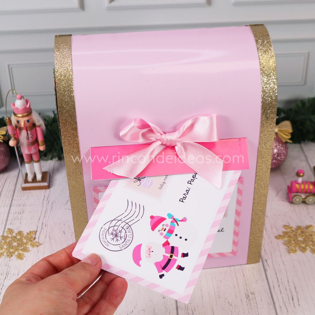 Sobre navideño entrando por la ranura del buzón de Papá Noel rosa con moño de raso · Masterclass de Navidad 2026