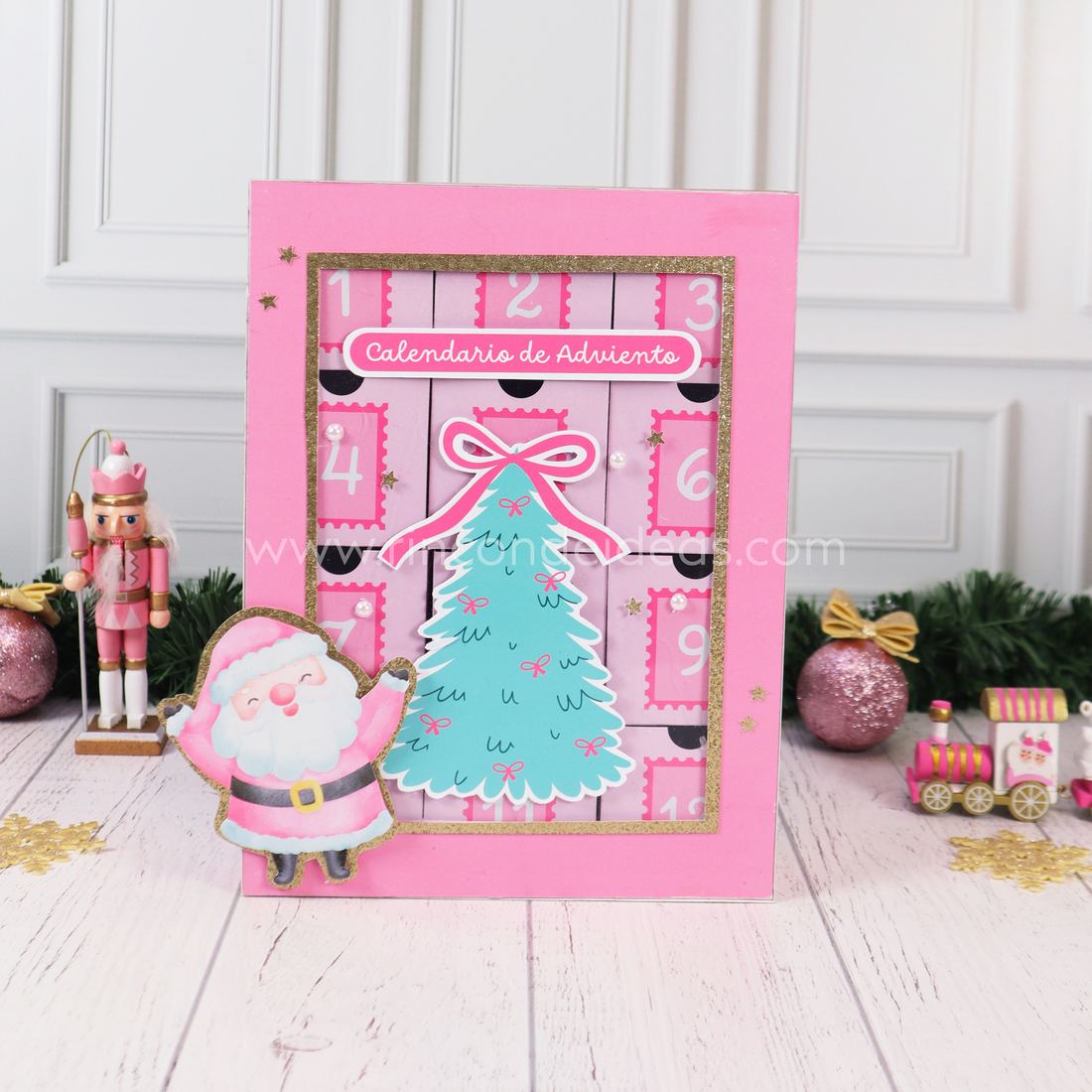 Calendario de Adviento con cajas, frente rosa con ventana de acetato, árbol verde agua y cajitas numeradas · Masterclass de Navidad 2026