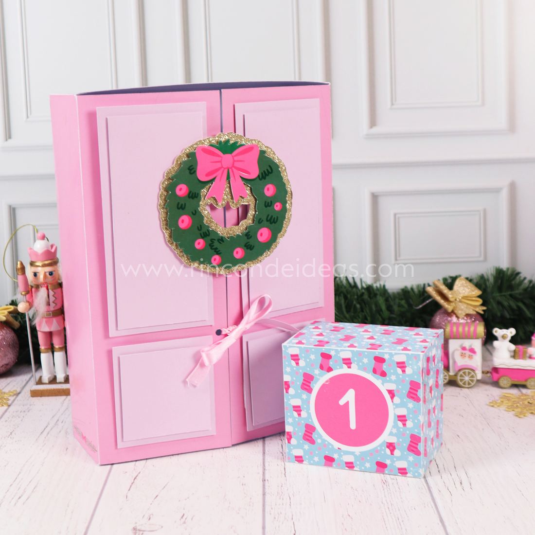 Calendario de Adviento con puertas rosa y corona, con una cajita de medias navideñas con el número 1 · Masterclass de Navidad 2026
