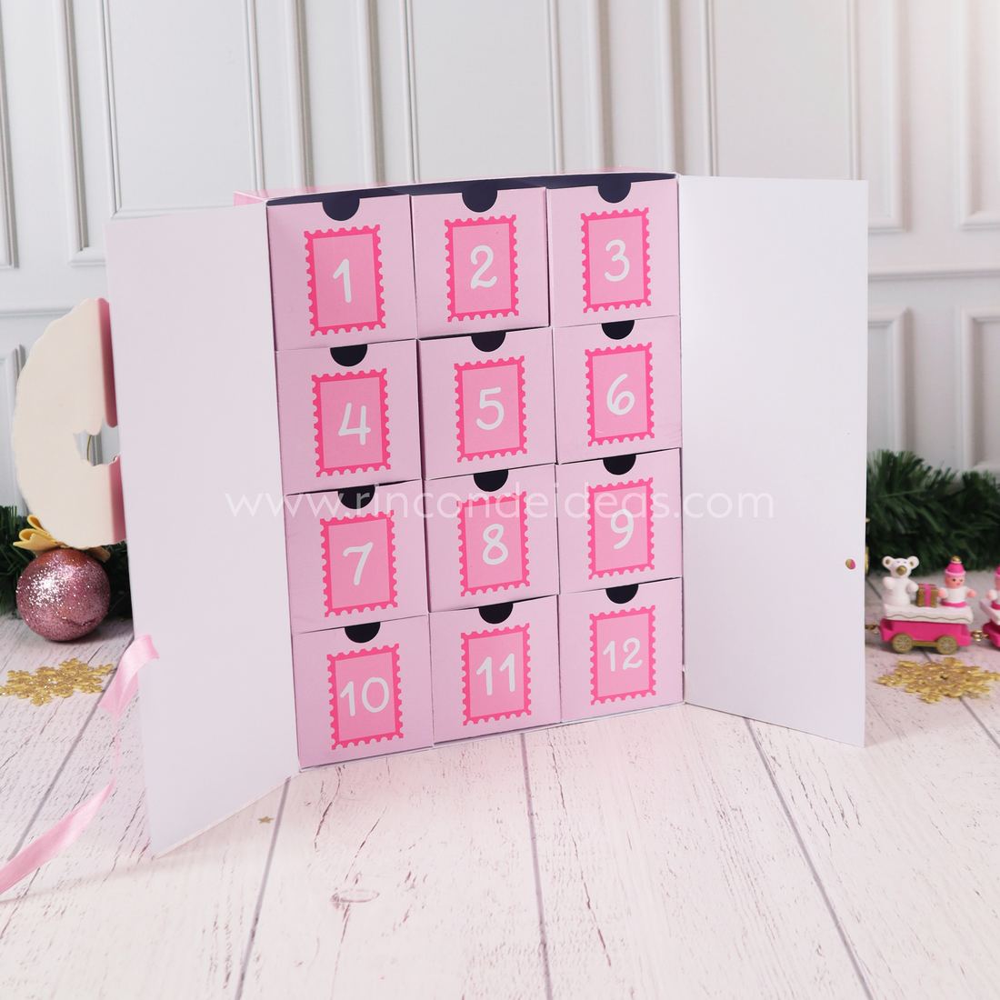 Calendario de Adviento con puertas blancas abiertas y 12 cajitas rosas numeradas con estampilla · Masterclass de Navidad 2026