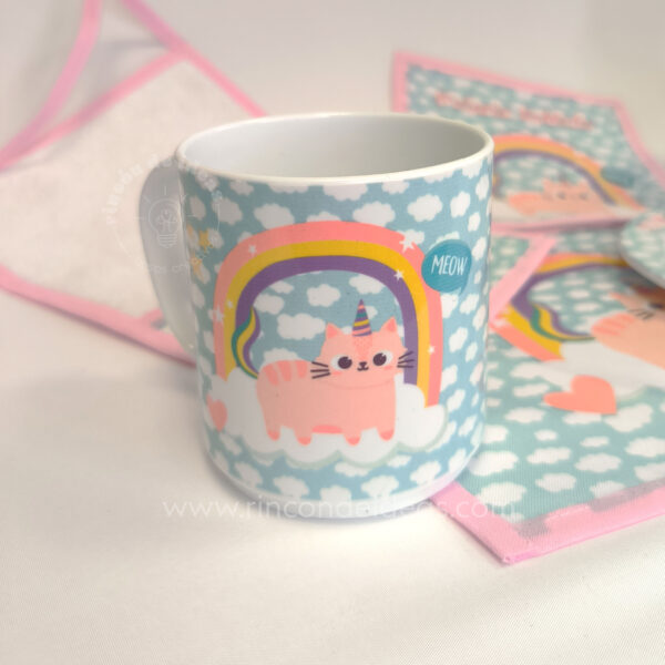 Taza sublimada de gatito unicornio apoyada sobre baberos con ribete rosa · Curso de Sublimación