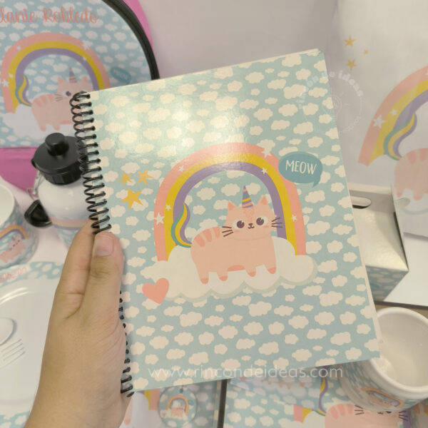 Mano sosteniendo un cuaderno anillado sublimado con gatito unicornio · Curso de Sublimación