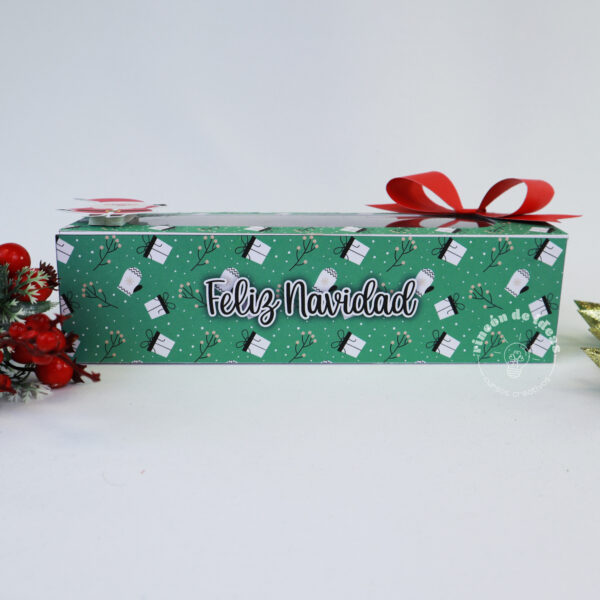 Caja alargada verde con estampado navideño, texto Feliz Navidad y moño rojo · Navidad en Rincón